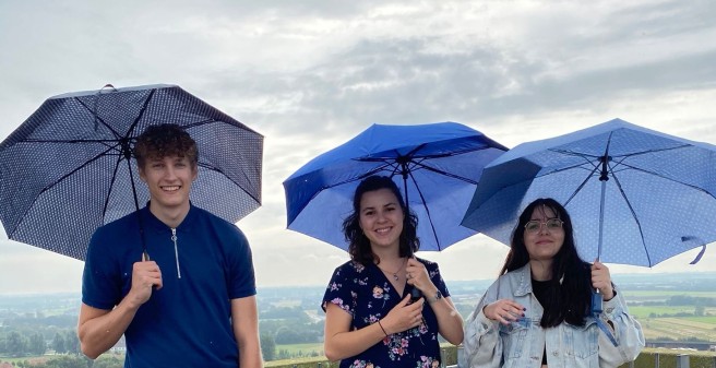 Leon Friedrichs und zwei Kommilitoninnen stehen draußen mit einem Regenschirm