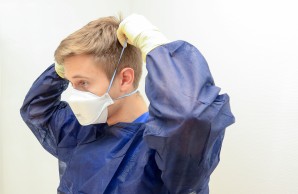 ein junger FSJler bindet sich eine Atemschutzmaske vor das Gesicht