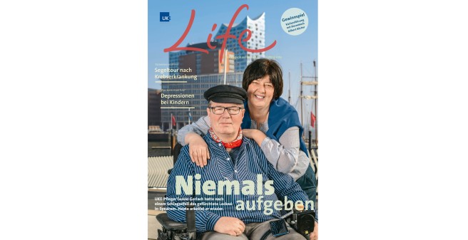 UKE Life Titelseite, Tomas Gerlach und Frau vor der Elphi, sie legt ihre Arme um seine Schultern, er sitzt im Rollstuhl