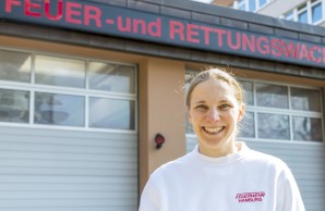 Notärztin Stefanie Beck lächelt strahlen in die Kamera, auf ihrem weißen Shirt steht Feuerwehr Hamburg