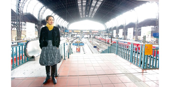 Professor Marylyn Addo lehnt am Geländer der Überführung, man blickt auf leere Bahnsteige des Hamburger Hauptbahnhofs