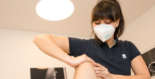 Physiotherapeutin Christina Hartojo behandelt ein Knie, Patient liegt