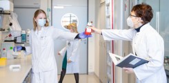 Drei Forscherinnen im Labor halten sichtbar Abstand 