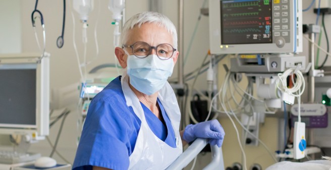 Ulrike Heidelbach, Intensivpflegerin im UKE steht am Bett einer Patientin in Schutzkleidung