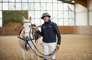 Parkinson - Polospieler Thomas Winter steht in der Reithalle mit einem weißen Pferd und hält einen Poloschläger über der Schulter