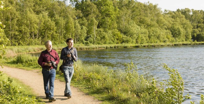 Simon Arndt und sein Vater gehen entlang eines Sees mit Kameras ausgerüstet