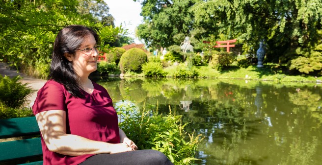 Prof. Karin Oechsle blickt in die Ferne, sie sitz in einer parkähnlichen Anlage in Hagenbek