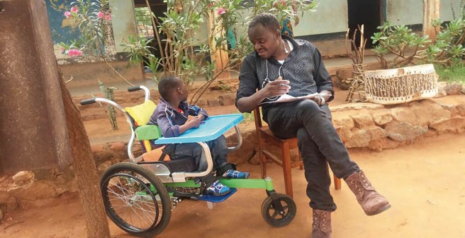 Arzt unterhält sich mit Kind, das im Rollstuhl sitzt, beide im Garten