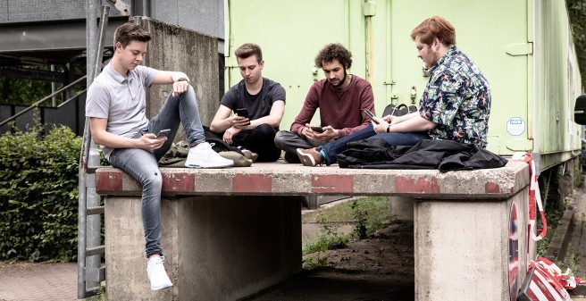 4 Jugendliche sitzen auf einer Mauer