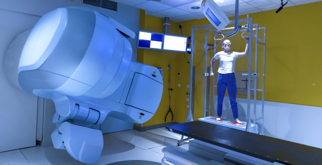 Im bestimmten Abstand zur Bestrahlungsquelle halten Patient:innen bis zu sechs verschiedene Arm- und Beinpositionen