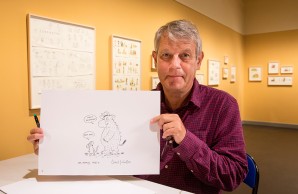 Axel Scheffler vor seinen Bildern in der Ausstellung mit einer Bleistiftzeichnung in der Hand