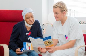 Pflegekraft zeigt einer stationärer Patientin einen Flyer mit Angeboten zu den angebotenen Wahlleistungen