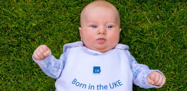 Das Bild zeigt ein Baby im Strampler mit der Aufschrift "Born in the UKE"